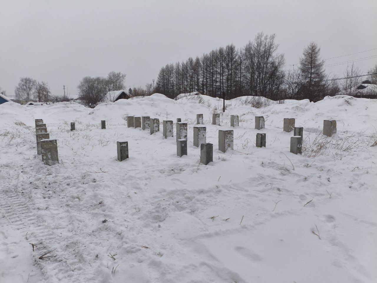 ЖБ сваи под жилой дом на заснеженном участке с деревянным забором и частными домами на фоне, Нижний Тагил