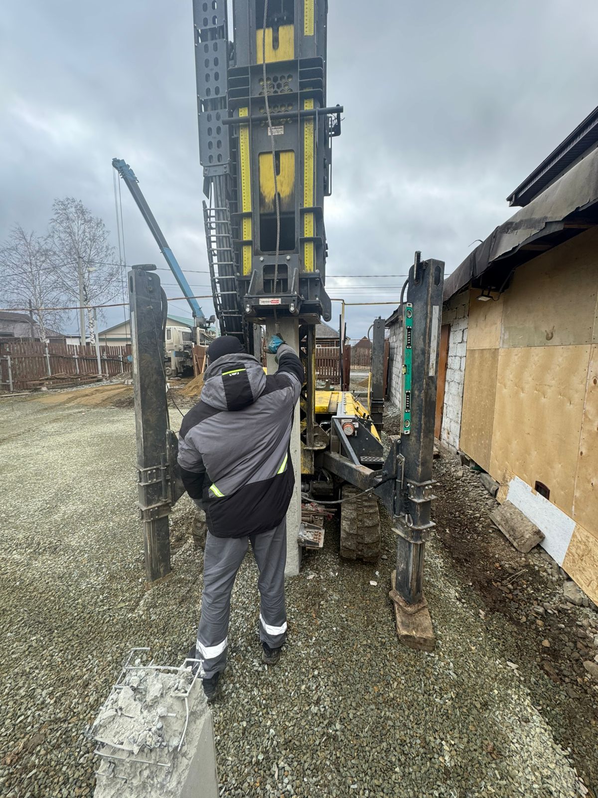 Рабочий контролирует забивку железобетонных свай С30.20 для основания жилого дома