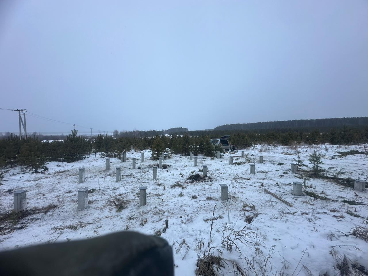 Забивка ЖБ свай С30.15 для фундамента жилого дома в деревне Ключи, участок среди хвойных деревьев зимой